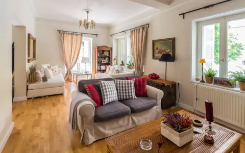 Przytulny salon w stylu angielskim z wygodnymi sofami, drewnianą podłogą i stylowymi dodatkami.