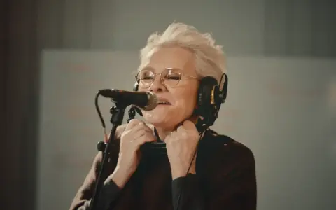 Eva Dahlgren med hörlurar och mikrofon, fångad i ett känslosamt ögonblick under en konsert.