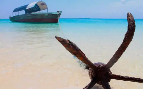 Kotwica na plaży, łódź na turkusowym morzu. Idealne miejsce na Zanzibar wycieczki fakultatywne.