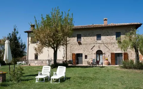 Un casale in pietra con giardino e lettini, perfetto per vacanze tranquille ad agosto in Italia.