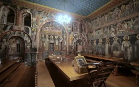 Inside Mount Athos, a refectory is adorned with ancient frescoes depicting religious scenes and figures.