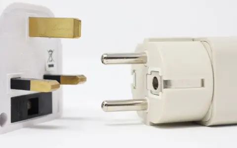 Reiseadapter für den Strom in Spanien. Ein britischer Stecker trifft auf einen europäischen Stecker.