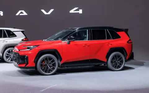 Czerwony, tani SUV z czarnym dachem i felgami, prezentowany na wystawie obok białego modelu.