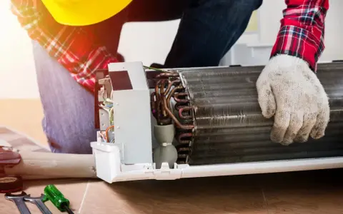 Técnico revisa unidad de aire acondicionado abierta. Mi aire acondicionado de casa no tiene fuerza, quizás por esto.