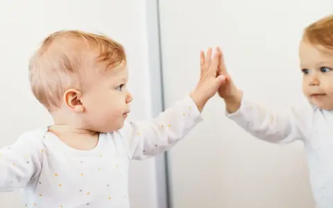 Bambino che tocca il suo riflesso, un momento chiave nella costruzione del sé nel bambino.
