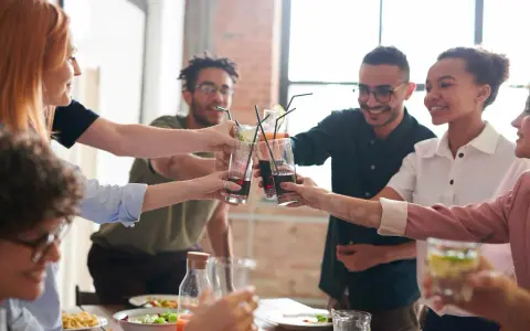 Grupo de amigos brindando con bebidas, inspirando temáticas para juegos de mesa y celebraciones.