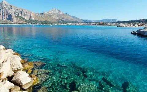Acque cristalline a San Vito Lo Capo, perfette per una vacanza con bambini. Montagne sullo sfondo, un sogno.