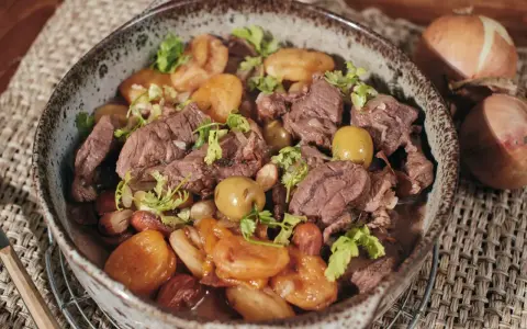 Un savoureux tajine de chevreuil mijoté avec des pommes de terre et des olives, garni de coriandre fraîche.