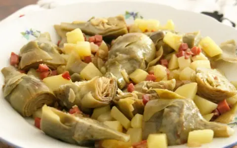 Plato de alcachofas tiernas y trocitos de jamón serrano, un clásico delicioso.