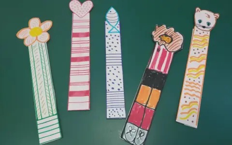 Cinco marcapáginas caseros: uno con flor, otro con corazón, uno con puntos, uno con un personaje y otro con un gatito.