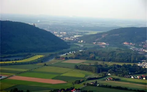 Blick über das Wesertal bei Porta Westfalica mit bewaldeten Hügeln, Feldern und der Stadt.