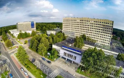 Widok z lotu ptaka na kompleks budynków szpitalnych otoczony zielenią.