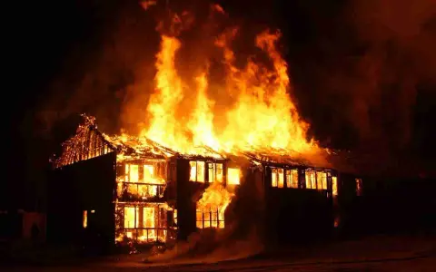 Une maison à deux étages est dévorée par les flammes, le toit s'effondre. L'incendie cause une destruction massive.