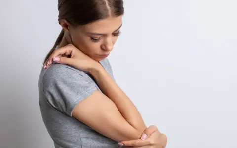 Mujer con dolor de codo, su piel con textura granulada se ve tensa.
