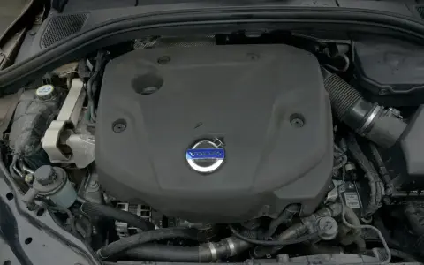 Silnik D4 Volvo pod czarną osłoną z niebieskim logo. Widać fragmenty przewodów i zbiornik płynu.
