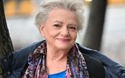 Uśmiechnięta Anna Seniuk, ikona polskich filmów, seriali i programów, w kolorowym szalu i granatowej kurtce.