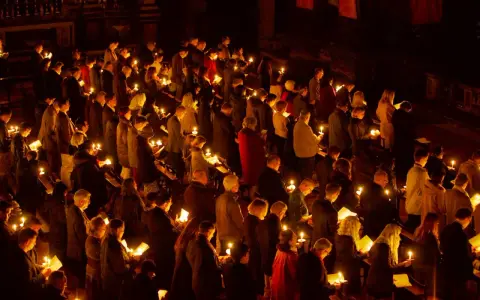 A solemn vigil unfolds as a congregation holds candles, their faces illuminated by the soft glow.