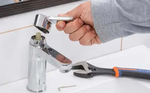 Mano desmontando grifo monomando. Llave inglesa y llave Allen cerca.