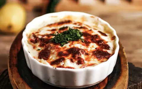 En krämig lasagne vegetarisk med gyllene ost och färska örter, serverad i en vit ugnsform.