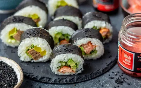 Gotowe sushi z łososiem i awokado, idealne do nauki jak zrobić sushi w domu. Obok słoiczek marynowanego imbiru.