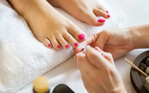 Piękne, różowe pedicure paznokcie u nóg są dopracowywane podczas zabiegu.
