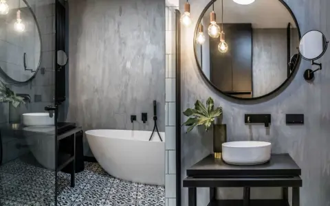 Nowoczesna łazienka w stylu loft z wolnostojącą wanną, umywalką nablatową i betonową ścianą.