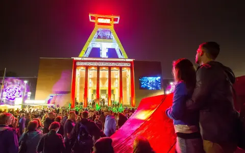 Ein Paar genießt die stimmungsvolle Nachtveranstaltung "Extraschicht Bochum" vor dem beleuchteten Deutschen Bergbau-Museum.