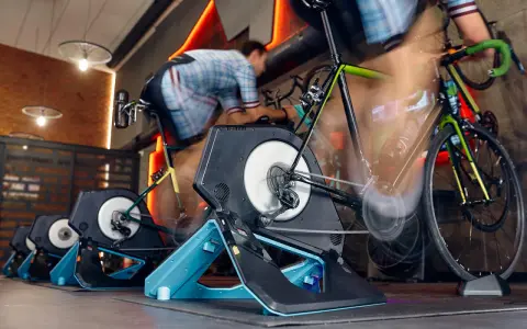 Intensywna jazda na rowerze w domu. Kilka rowerów stacjonarnych z trenażerami w akcji, tworząc wrażenie ruchu.