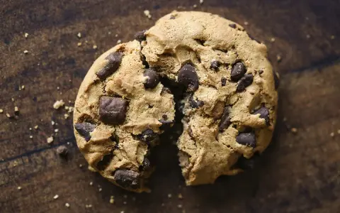 Un cookie aux pépites de chocolat, brisé en deux, révèle sa texture moelleuse. La meilleure recette de cookies pour un goûter gourmand.