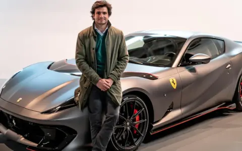 Carlos Sainz posa junto a un Ferrari gris mate, listo para la próxima carrera.