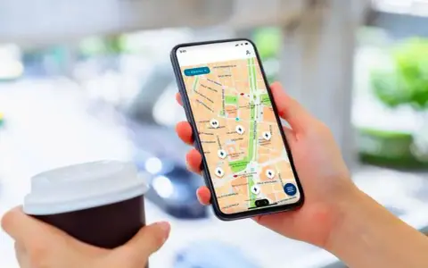 Persona usa un app cargadores eléctricos en su móvil para encontrar puntos de recarga en un mapa.