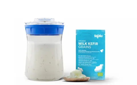 Kefirko Bio Milch Kefir Körner für gesunden Kefir. Ein Glas mit Kefir und eine Packung mit Kefir-Körnern.