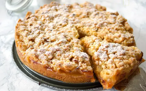 Ein goldbrauner Apfelkuchen mit Streuseln, bestäubt mit Puderzucker. Dieses Apfelkuchen Rezept sieht köstlich aus!