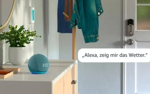 Alexa Routine erstellen: Ein blauer Echo Dot mit leuchtender Uhrzeit und eine Pflanze stehen auf einer Kommode. Eine Jacke hängt an einem Kleiderständer.
