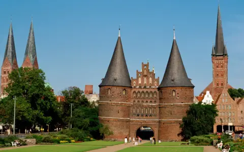 Holstentor in Lübeck, ein Wahrzeichen für Ihre **Ferien Schleswig-Holstein 2025**. Historische Backsteinarchitektur mit Türmen und grünen Parks.