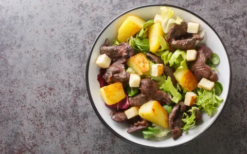 Salade de gésiers savoureuse avec pommes de terre rôties, croûtons et salade verte fraîche. Un délice pour les amateurs de cuisine française.
