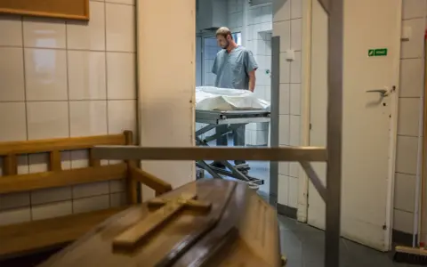 W prosektorium, po sekcji zwłok, pracownik pochyla się nad noszami. Czy po sekcji zwłok można otworzyć trumnę?