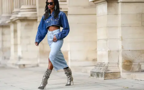 Modella con giacca di jeans corta e gonna lunga, stivali argento scintillanti. Un look che ricorda la moda degli anni '80.
