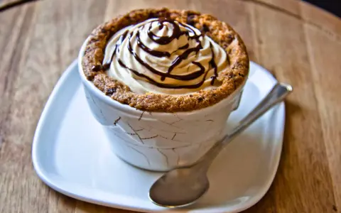 Un délicieux dessert dans une tasse en cookies, garni de crème fouettée et de sauce au chocolat.