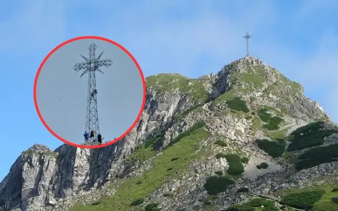Ludzie wspinają się na krzyż na Giewoncie. Czy krzyż na Giewoncie świeci? Widać go z daleka na tle błękitnego nieba.