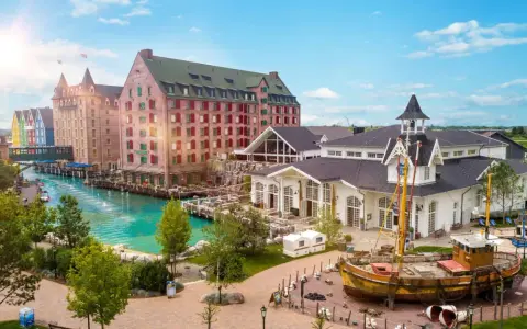 Ein malerischer Kanal fließt vorbei an bunten Gebäuden und einem alten Schiff. Das ist das charmante Themenhotel im Europa-Park.