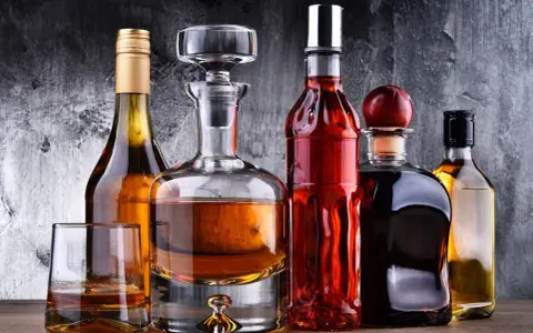 Karafka z koniakiem i inne butelki z brandy na drewnianym blacie.