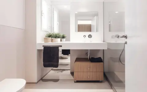 Baño moderno con lavabo flotante, mueble de madera y plantas. Ideal para quienes buscan reformar baño precio.