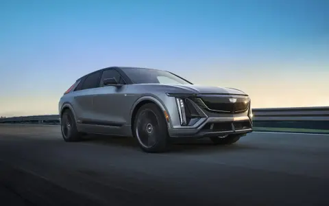 Cadillac Lyriq, un SUV eléctrico que representa el futuro de las marcas americanas de coches, avanza por una carretera al atardecer.