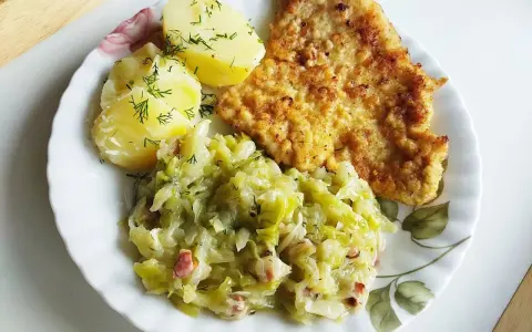 Kotlet schabowy z ziemniakami i młodą kapustą zasmażaną z boczkiem.