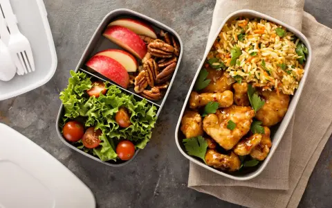 Pyszne śniadanie do pracy: kurczak w sosie, ryż z warzywami, sałatka z pomidorkami, jabłka i orzechy.