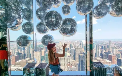Kobieta cieszy się widokiem z Summit One Vanderbilt, otoczona lśniącymi kulami.