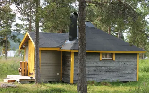 En mysig stuga för camping i Kiruna, omgiven av skog och med en sjö i bakgrunden.