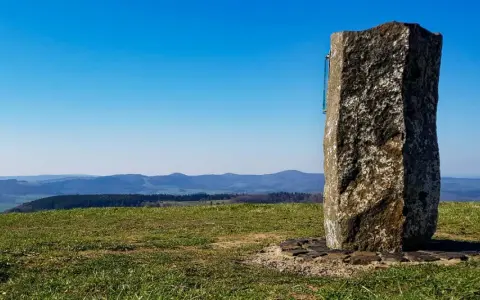 Steinerner Gedenkstein auf der Wasserkuppe mit Blick über Hügel und Täler.