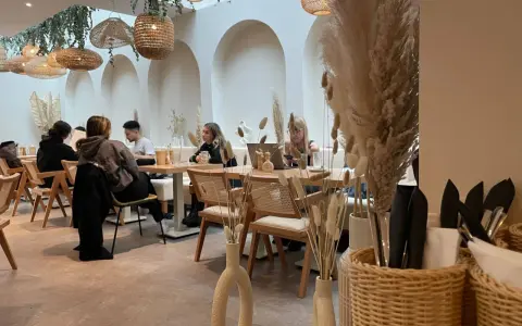 Gemütliches Café mit Boho-Deko, geflochtenen Lampen und Trockenblumen. Gäste genießen ihren soul brunch in entspannter Atmosphäre.